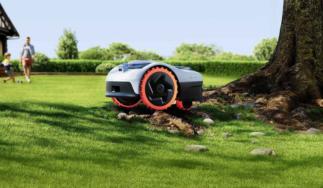 Navimow i2 AWD robotic mower navigating around a tree on a residential lawn